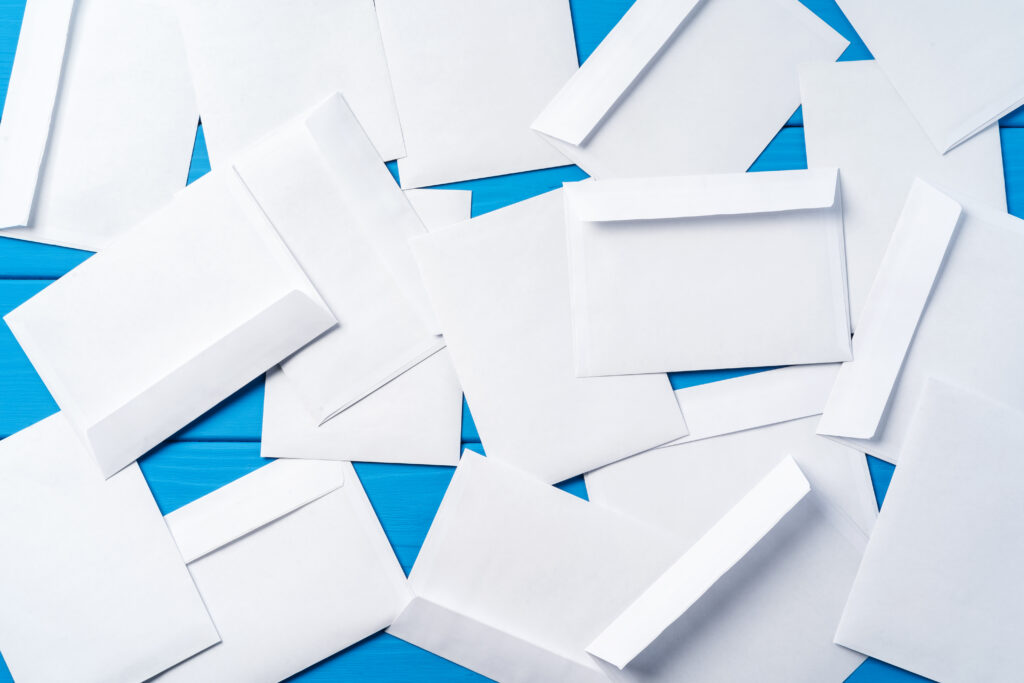 A scattered stack of white envelopes on a blue surface.