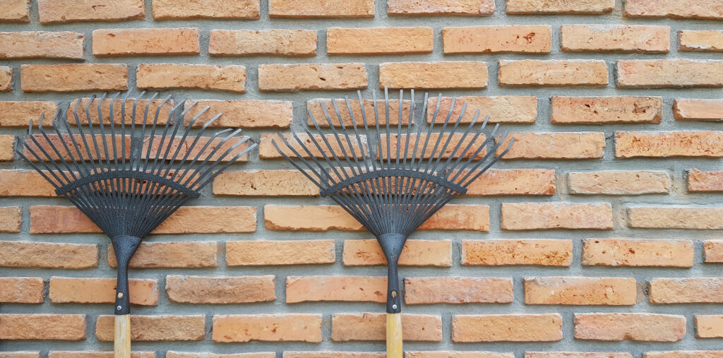 Two rakes against brick bldg